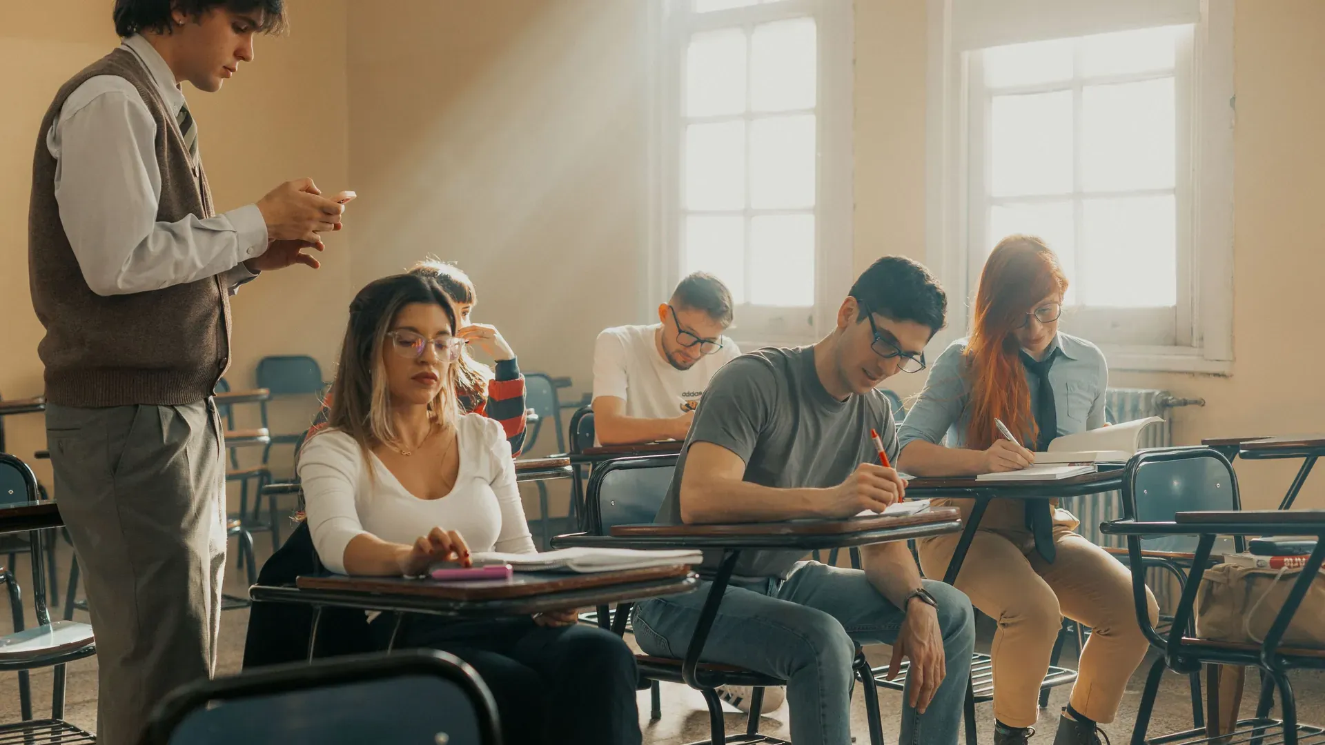 Instructor acompañando a un grupo de alumnos adultos sentados en pupitres