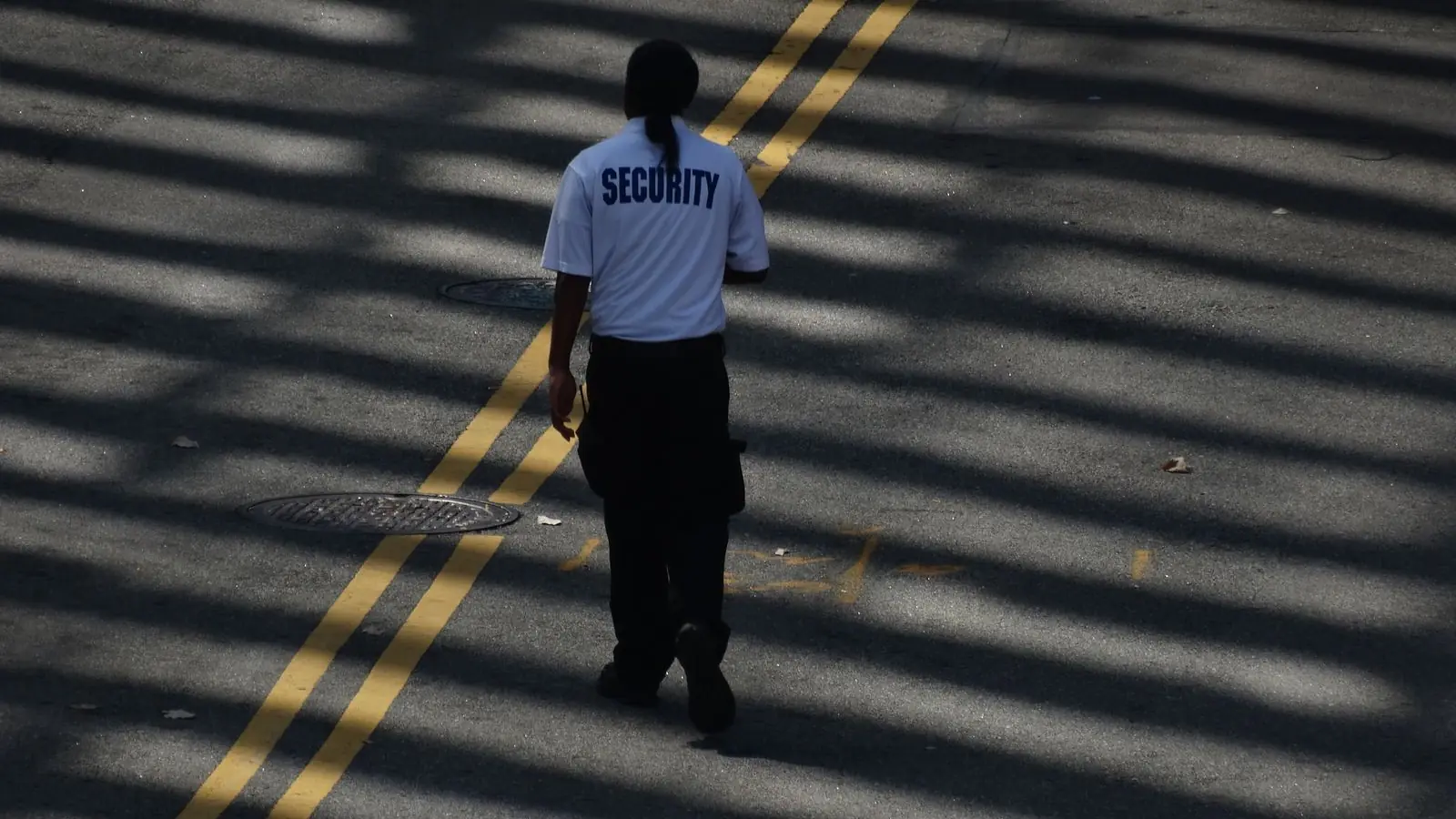 Guardia de seguridad de espaldas recorriendo una calle durante su ronda de vigilancia